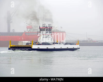 William G. Burnett Fähre Transporte Fahrzeuge über Corpus Christi Ship Channel im Nebel. Port Aransas, Texas USA. Tanker im Hintergrund. Stockfoto