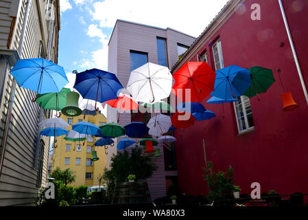 Bunte Sonnenschirme und Laternen zwischen zwei Gebäuden in Bergen, Norwegen ausgesetzt. Stockfoto