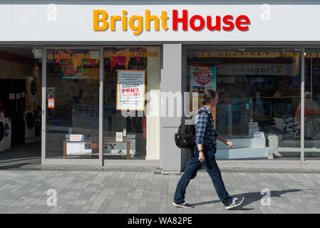 Ein Mann hinter der Fassade eines BrightHouse shop auf Newport Street in Bolton, Lancashire, Großbritannien. (Nur redaktionelle Nutzung). Stockfoto