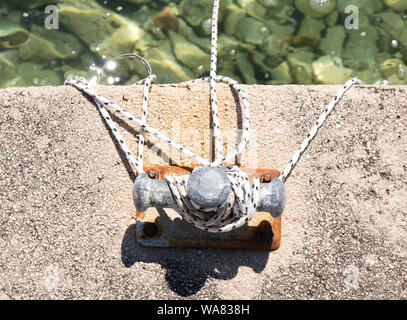 Kleine Poller mit Seil auf ein flaches Meer Pier Stockfoto