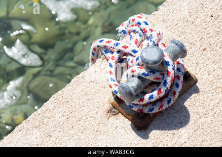 Kleine Poller mit Seil auf ein flaches Meer Pier Stockfoto