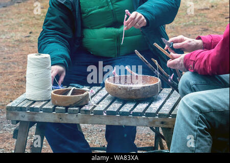 Arbeitnehmer Verkleidung Dochte und bereiten Sticks für Menschen Kerzen über einem Lagerfeuer zu machen, während einer Veranstaltung in Michigan, USA Stockfoto