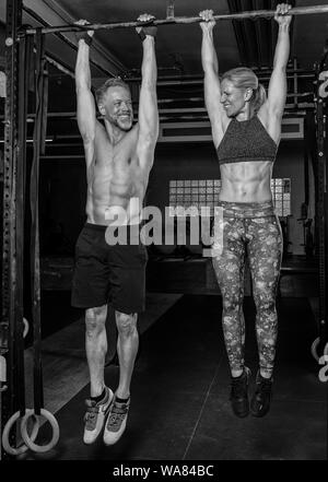 Ein attraktives Paar mittleren Alters zusammen tut, ein Fitness Training und Spaß haben. Starke ältere Mann und Frau hängen auf der horizontalen Leiste. Stockfoto