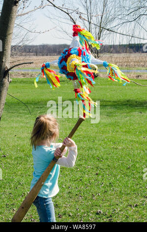 Junge Mädchen schwingt einen base ball bat zu einem bunten Pinata Stockfoto