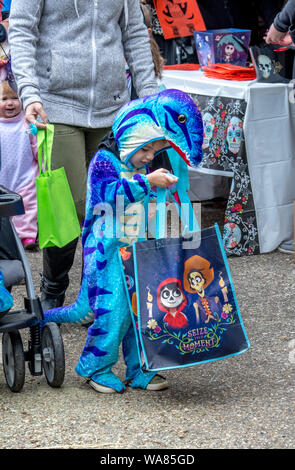 Oktober 27, 2018 Coloma MI USA; ein kleiner Junge in einem Dinosaurier Kostüm blickt in seinem bonbontüte, um zu sehen, alle die Leckereien im Inneren Stockfoto