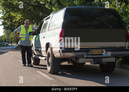 Ein reifer Mann, der neben seinem Pickup truck in sonniger Umgebung im Freien. Stockfoto