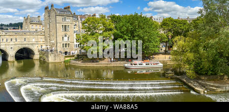 BATH, ENGLAND - Juli 2019: Panoramablick auf das hufeisenförmige Pulteney Wehr auf den Fluss Avon und die Pulteney Bridge in der Mitte der Badewanne. Stockfoto