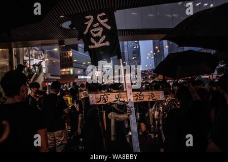 Eine Demonstrantin hält ein hölzernes Kreuz mit der Aufschrift 'Devil regelt das Hongkong" während der Demonstration. Demonstranten auf die Straße gingen, an einem regnerischen Sonntag in einem pro-demokratischen Demonstration auf der Insel Hong Kong, verlangen Sie die vollständige Rücknahme der Auslieferung Bill und die Regierung auf, eine unabhängige Untersuchung der jüngsten Zusammenstöße zwischen Demonstranten und Polizei - Organisatoren erklärte, dass dies der größte Rallye war während der Woche zu setzen. Stockfoto