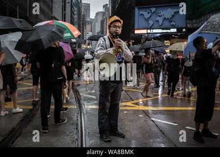 Ein Mann spricht über Megaphon orientieren Demonstranten während der Demonstration. Demonstranten auf die Straße gingen, an einem regnerischen Sonntag in einem pro-demokratischen Demonstration auf der Insel Hong Kong, verlangen Sie die vollständige Rücknahme der Auslieferung Bill und die Regierung auf, eine unabhängige Untersuchung der jüngsten Zusammenstöße zwischen Demonstranten und Polizei - Organisatoren erklärte, dass dies der größte Rallye war während der Woche zu setzen. Stockfoto