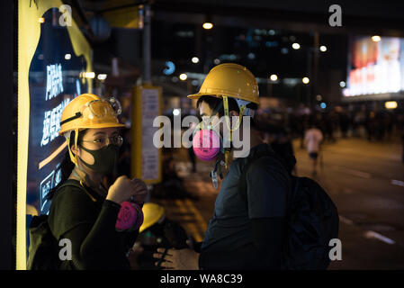 Die Demonstranten passen ihre Gesichtsmasken während einer friedlichen Demonstration. Demonstranten verhöhnt Polizei Aufträge und marschierten von Causeway Bay in Sheung Wan. Trotz starker Regen, über eine Million Teilnehmer friedlich demonstrierten in Unterstützung der anti-Auslieferung Bewegung. Veranstalter Schätzung 1,7 Millionen Menschen an der Kundgebung teilgenommen, während Polizei die Zahl auf unter 500.000. Stockfoto