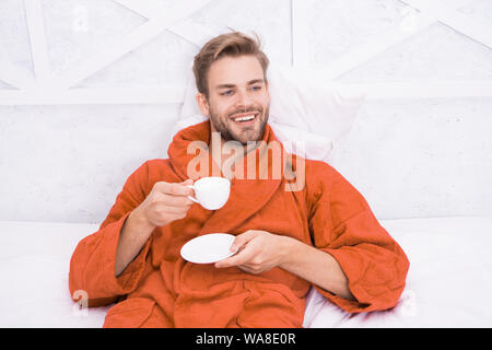 Ab Tag mit guten Kaffee. Entspannt zu Hause. Angenehme Momente. Gourmet Espresso. Kaffee am Morgen genießen. Gerne morgen. Schöner Mann trinken Kaffee am Morgen. Happy bärtiger Mann im Bett. Gute Laune. Stockfoto