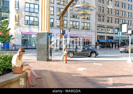 Frau sitzt im Playhouse Square Theatre District in der Nähe des größten Kronleuchters im Freien der Welt an der Euclid Avenue in Cleveland, Ohio, USA. Stockfoto