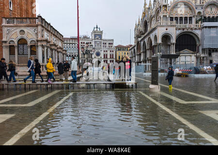 Menschen zu Fuß auf erhöhten Plattformen während der Acqua Alta (hohe Wasser) Fall, Piazzetta di San Marco, Venedig, Italien Stockfoto