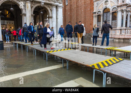 Menschen zu Fuß auf erhöhten Plattformen während der Acqua Alta (hohe Wasser) Fall, Markusplatz, Venedig, Italien Stockfoto