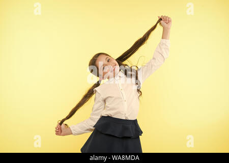 Deal mit langem Haar frisur. Kid girl langen pferdeschwanz Frisur. Kind Schuluniform machen Frisur. Kid stilvolle modischen posieren Pferdeschwänze halten Frisur. Komfortable und einfache Frisur. Stockfoto