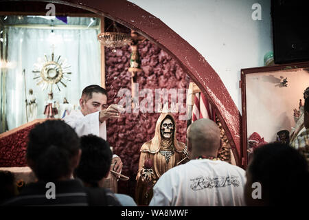 Anhänger von Nuestra Señora de la Santa Muerte (Unsere Liebe Frau von Heiligen Tod) besuchen Sie die Iglesia Santuario Nacional del Angel de la Santa Muerte in Tepito, Mexiko Stadt. Santa Muerte ist der Schutzpatron der Verbrecher, Prostituierte, Drogenabhängige, und alle, die von der Gesellschaft übersehen. Eine Personifikation des Todes, ist sie mit Heilung, Schutz und sichere Lieferung ins Jenseits von ihrer Anhänger. Stockfoto