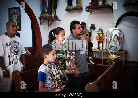 Anhänger von Nuestra Señora de la Santa Muerte (Unsere Liebe Frau von Heiligen Tod) besuchen Sie die Iglesia Santuario Nacional del Angel de la Santa Muerte in Tepito, Mexiko Stadt. Santa Muerte ist der Schutzpatron der Verbrecher, Prostituierte, Drogenabhängige, und alle, die von der Gesellschaft übersehen. Eine Personifikation des Todes, ist sie mit Heilung, Schutz und sichere Lieferung ins Jenseits von ihrer Anhänger. Stockfoto