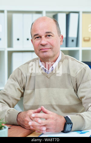 Portrait von positiven zuversichtlich Reife Unternehmer sitzen am Tisch und auf der Suche an Kamera Stockfoto