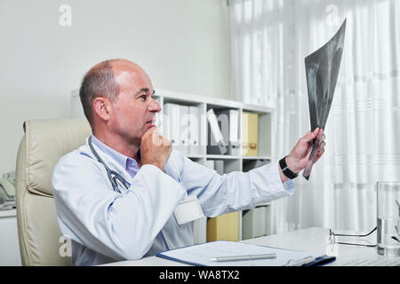 Nachdenklich reife Arzt Lunge x-ray von petient mit Pneumonie suchen Stockfoto
