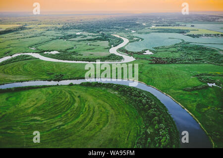 Luftaufnahme grüne Wiese und Flusslandschaft im sonnigen Frühling Abend. Blick von oben auf die schöne Natur von hohen Haltung im Sommer. Drone Stockfoto