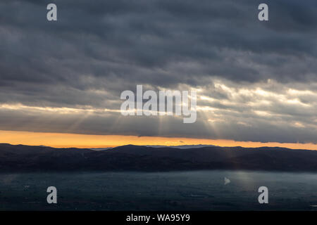 Sonnenstrahlen herab, von ein paar Wolken über ein Tal mit Nebel gefüllt, leuchtenden Teil Stockfoto