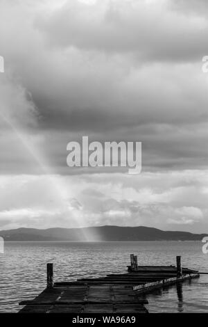 Schönen Blick auf einen Regenbogen über einen Steg auf einem See Trasimeno (Umbrien, Italien) Stockfoto