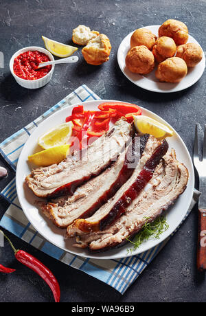In Scheiben geschnitten auf einer weißen Platte auf einer konkreten Tabelle mit jamaikanischen frittierte Klöße und Hot Chili Sauce, vertikale Ansicht von oben Stockfoto