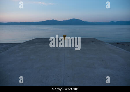 Bootsplatz, Liegeplatz auf dem blauen Meer in der Dämmerung. Malerische Seenlandschaft in der Abenddämmerung. Ein Schiff der zugewiesenen Platz an einem Wharf oder Dock. Kai für Boote, Schiffe, Büchsen. Der Küstengebiete. Dämmerung am Kai, Dock. Platz kopieren Stockfoto