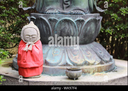 Steinerne Statue von lächelnden Jizo (Jizo Bosatsu) in einer Strickmütze, Kobe (Kobe-shi), Japan Stockfoto