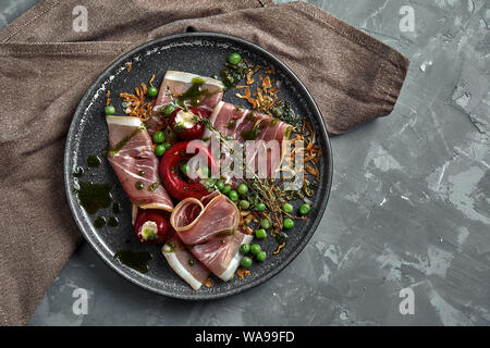 Italienische Prosciutto Crudo und jamon mit Rosmarin. Rohen Schinken auf einer konkreten grauen Hintergrund. Close-up Stockfoto