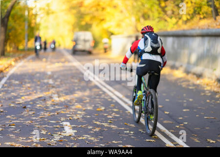 Nicht erkennbare Kerl, zurück zu uns Reiten Fahrrad im Herbst Park, farbenfrohe Bäume, sonnigen Tag, Herbst Laub. Gesunder Lebensstil, Freizeit Aktivität Stockfoto