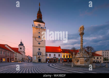 Trnava, Slowakei - 9. April 2019: City Tower und Heilige Dreifaltigkeit Statue auf dem Hauptplatz von Trnava, Slowakei. Stockfoto