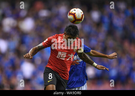 Brasilianische Fußballspieler Paulinho, oben, von Guangzhou Evergrande Taobao leitet den Ball gegen einen Spieler von Shanghai Shenhua in Grönland ihr 15. ro Stockfoto