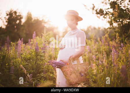 Schwangere Frau mit einem strohkorb mit Wildblumen Stockfoto