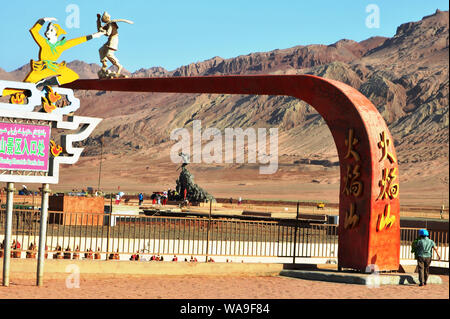 Touristen posieren für Fotos mit den Sehenswürdigkeiten Skulptur am Fuße des Huoyan (Flaming) Berg in Turpan Becken, im Nordwesten Chinas Xinjiang Uygur au Stockfoto