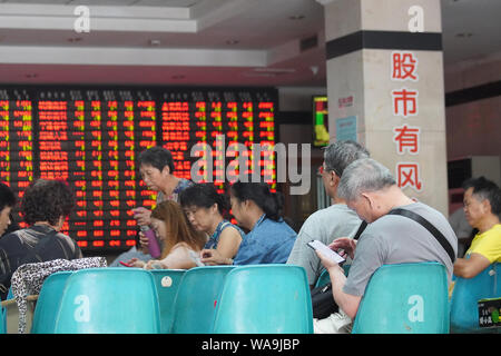 Chinesische Investoren Blick auf einen Bildschirm, der Index und die Preise der Aktien (rot für Preis steigt und grün für den Preis fallen) auf einer Börse brokerage House Stockfoto