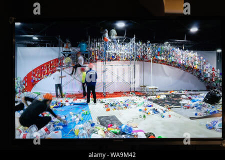 Chinesische Arbeiter montieren eine Kunstinstallation von Hunderten von Plastikflaschen während der Ausstellung unter dem Motto "Ära der Kunststoffe: Eine Elegie von Albatross gemacht Stockfoto