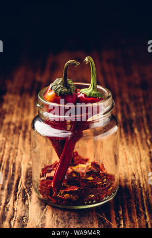 Zwei getrocknete rote Chilischoten in Jar mit gemahlenem Pfeffer Stockfoto