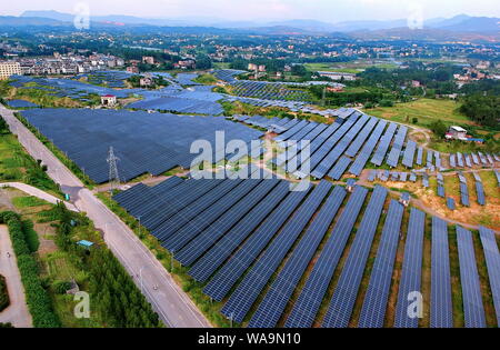 ------ Luftbild von Arrays von Solarmodulen um die Berge und auf dem Dach der Gebäude in Changjiang Dorf installiert, Zhoutian Stadt, Hui Stockfoto