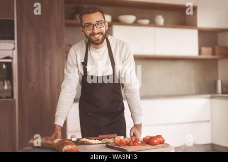 Mann in eine Schürze in Scheiben Salami Sandwiches Stockfoto