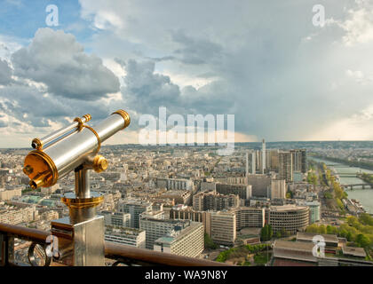 Münz-Teleskop auf dem Eiffelturm Aussichtsplattform. Auf der Suche nach Südwesten entlang der Seine und mit Regen Wolken Dusche. Paris, Frankreich Stockfoto