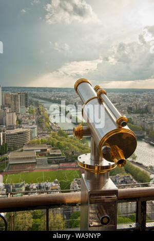 Münz-Teleskop auf dem Eiffelturm Aussichtsplattform. Auf der Suche nach Südwesten entlang der Seine und mit Regen Wolken Dusche. Paris, Frankreich Stockfoto