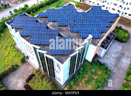 ------ Luftbild von Arrays von Solarmodulen um die Berge und auf dem Dach der Gebäude in Changjiang Dorf installiert, Zhoutian Stadt, Hui Stockfoto