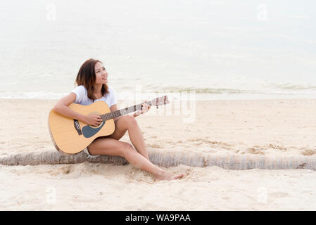 Junge Frau mit Gitarre am Strand. Musiker Lebensstil. Travel Concept. Stockfoto