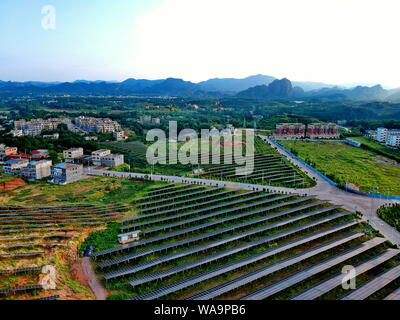 ------ Luftbild von Arrays von Solarmodulen um die Berge und auf dem Dach der Gebäude in Changjiang Dorf installiert, Zhoutian Stadt, Hui Stockfoto