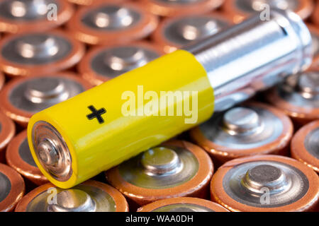Mehrere verwendeten AA-Alkali-Mangan-Batterien und einer einzigen AAA-Batterie werden gesehen in einem Stapel angeordnet. Closeup Seitenansicht von plus Seite der Batterie. Single Stockfoto