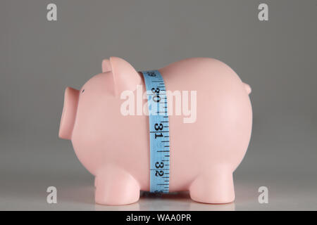 Maßband um Sparschwein ein Konzept der "Knappen Budget" Stockfoto