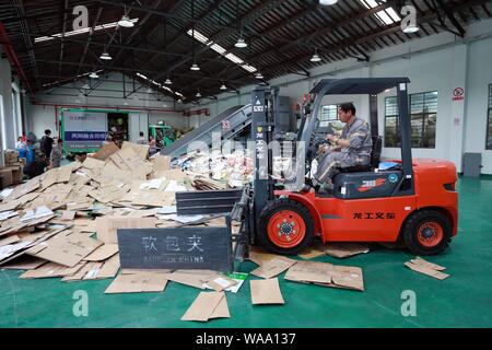 Ein chinesischer Arbeiter sortiert Recycling Abfall, der auf einer Distribution Center der erneuerbaren Energien Abfälle aus Behälter bereitgestellt werden, um das neue Müll sortieren s gerecht zu werden gesammelt Stockfoto