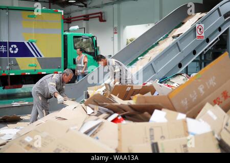 Ein chinesischer Arbeiter sortiert Recycling Abfall, der auf einer Distribution Center der erneuerbaren Energien Abfälle aus Behälter bereitgestellt werden, um das neue Müll sortieren s gerecht zu werden gesammelt Stockfoto