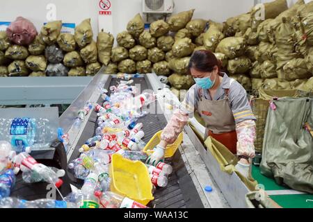 Ein chinesischer Arbeiter sortiert Recycling Abfall, der auf einer Distribution Center der erneuerbaren Energien Abfälle aus Behälter bereitgestellt werden, um das neue Müll sortieren s gerecht zu werden gesammelt Stockfoto